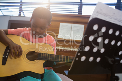 Boy playing guitar while sitting in classroom