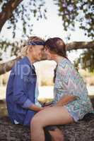 Side view of smiling romantic couple sitting on tree trunk