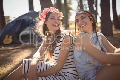 Portrait of smiling friends sitting on field against tent