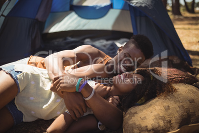 Close of happy couple lying on field against tent