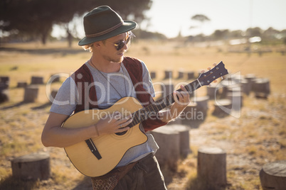 Young man playing guitar while standing on field