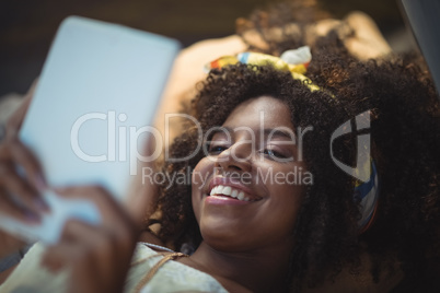 Smiling woman using tablet while lying in tent