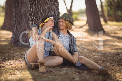 Cheerful couple sitting by tree trunk