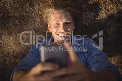 Overhead view of man smart phone while lying on field