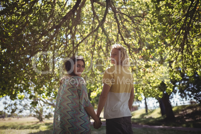 Rear view portrait of couple holding hands while standing on field