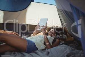 Young woman using digital tablet while lying down in tent