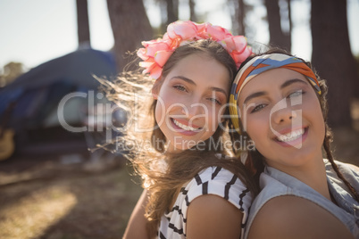 Close up portrait of smiling friends sitting on field against tent
