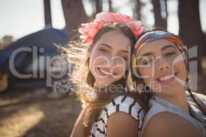 Close up portrait of smiling friends sitting on field against tent