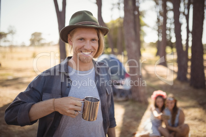 Portrait of man holding cup while standing against friends