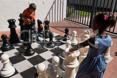 Classmates playing with large chess at school