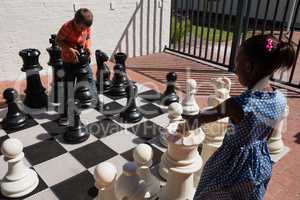 Classmates playing with large chess at school