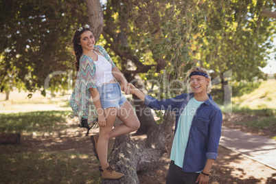 Portrait of smiling couple playing on tree trunk