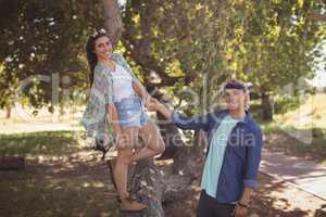 Portrait of smiling couple playing on tree trunk