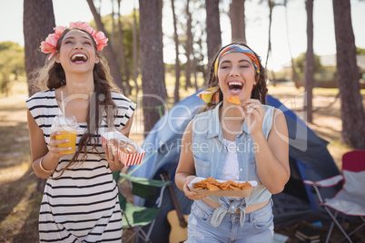 Happy friends eating snacks while camping in forest