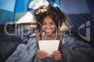 Portraitn of happy woman using digital tablet while lying down in tent