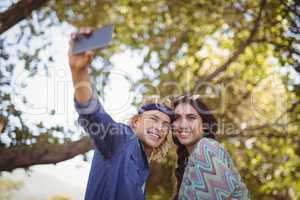 Happy couple taking selfie against trees