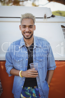 Portrait of man holding beer glass against van