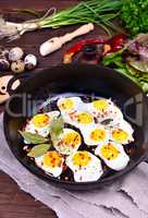 Black cast-iron frying pan with fried quail eggs