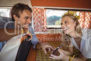 Cheerful woman showing mobile phone to man in van