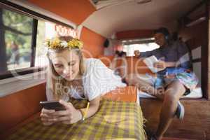 Woman using phone with man holding tablet in van