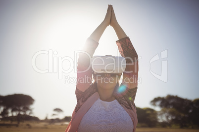 Woman exercising while using virtual reality glasses against blue sky