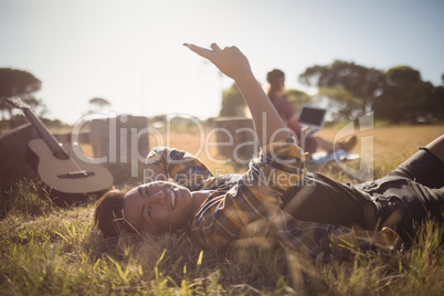 Portrait of smiling young man using mobile phone while lying on field