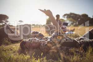 Portrait of smiling young man using mobile phone while lying on field