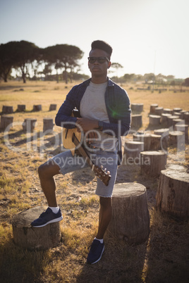 Full length of man standing with guitar at forest