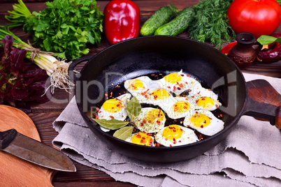 Fried quail eggs in a cast-iron frying pan