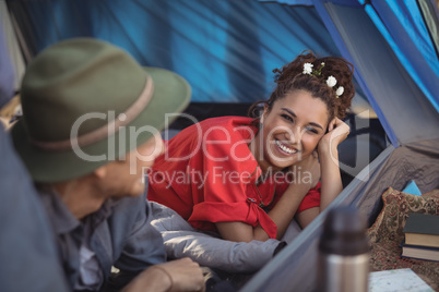 Happy couple relaxing in tent at forest