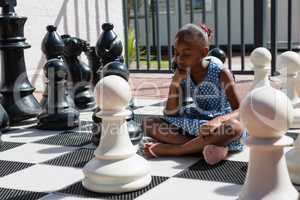 Close up of thoughtful girl sitting by chess pieces