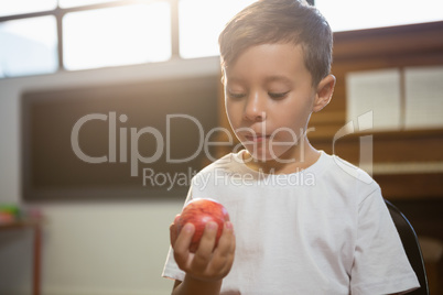 Close up of boy holding apple while standing against piano
