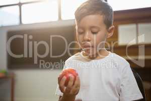 Close up of boy holding apple while standing against piano