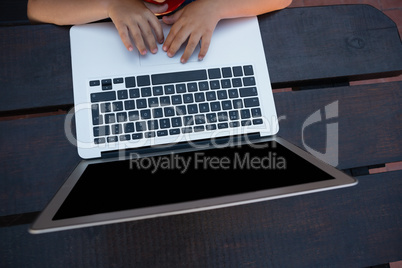 Overhead view of boy using digital laptop while sitting at table