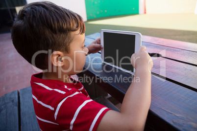 Side view of cute boy holding digital tablet