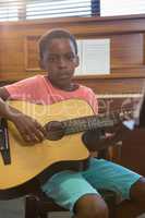 Portrait of boy playing guitar in class