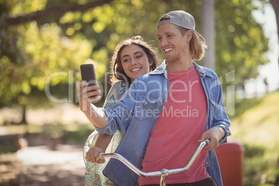 Happy couple looking at smart phone while riding bicycle