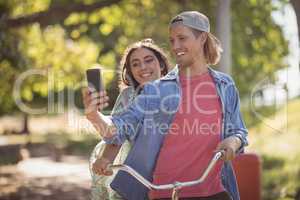 Happy couple looking at smart phone while riding bicycle