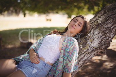 Close up of young woman relaxing on tree trunk