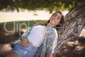 Close up of young woman relaxing on tree trunk