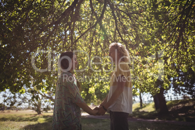 Side view of couple holding hands while standing on field