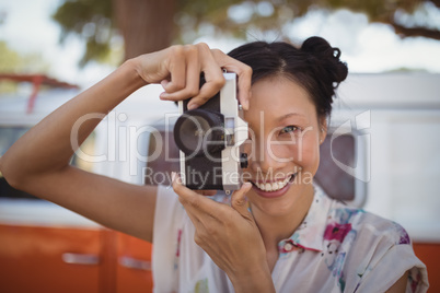 Portrait of woman photographing while standing against van