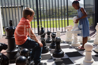 Classmates playing together with large chess