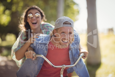 Happy couple riding bicycle against tree