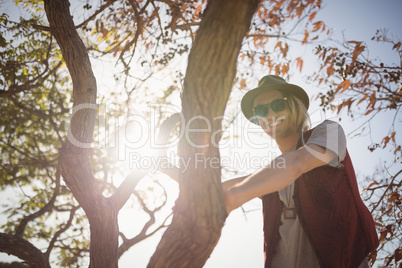 Low angle portrait of smiling man standing on tree