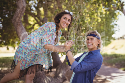 Side view portrait of couple playing on tree trunk