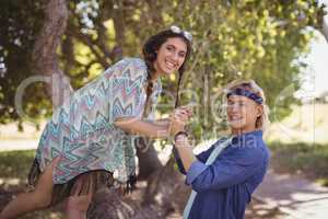 Side view portrait of couple playing on tree trunk