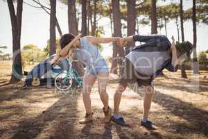 Full length of playful couple dabbing while standing on field