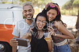Happy woman with friends taking selfie from mobile phone
