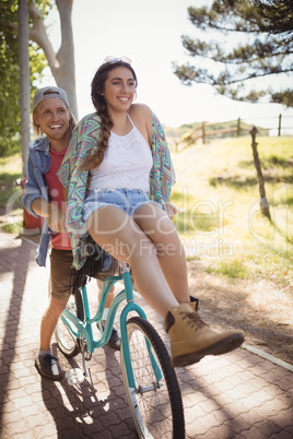 Smiling couple sitting on bicycle at footpath